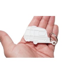 Brelok w kształcie białej mini przyczepy kempingowej Niewiadów N126N z białym oknem prezentowany na dłoni